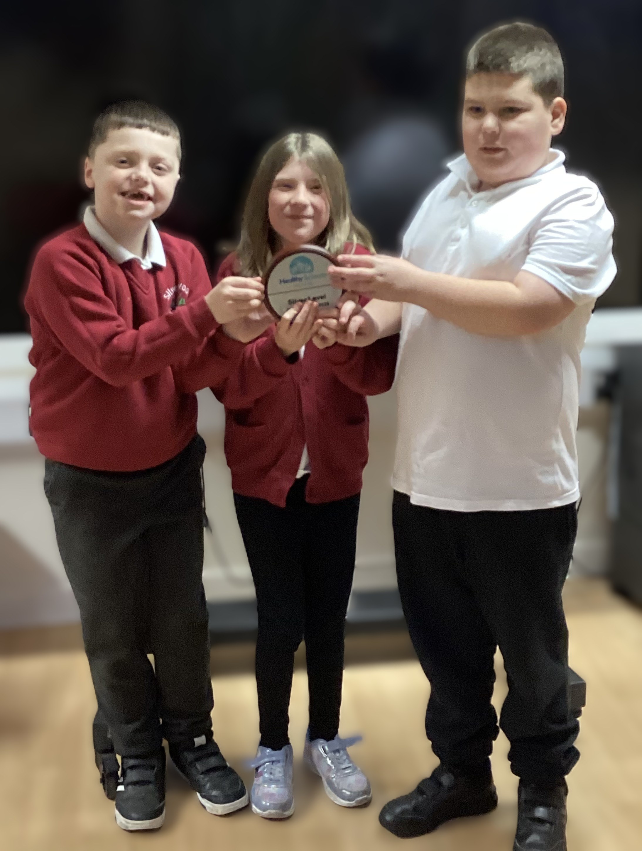 Three Silverwood School pupils proudly showing their Silver Award